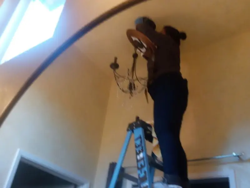 Electrician installing a chandelier in a Merced residence